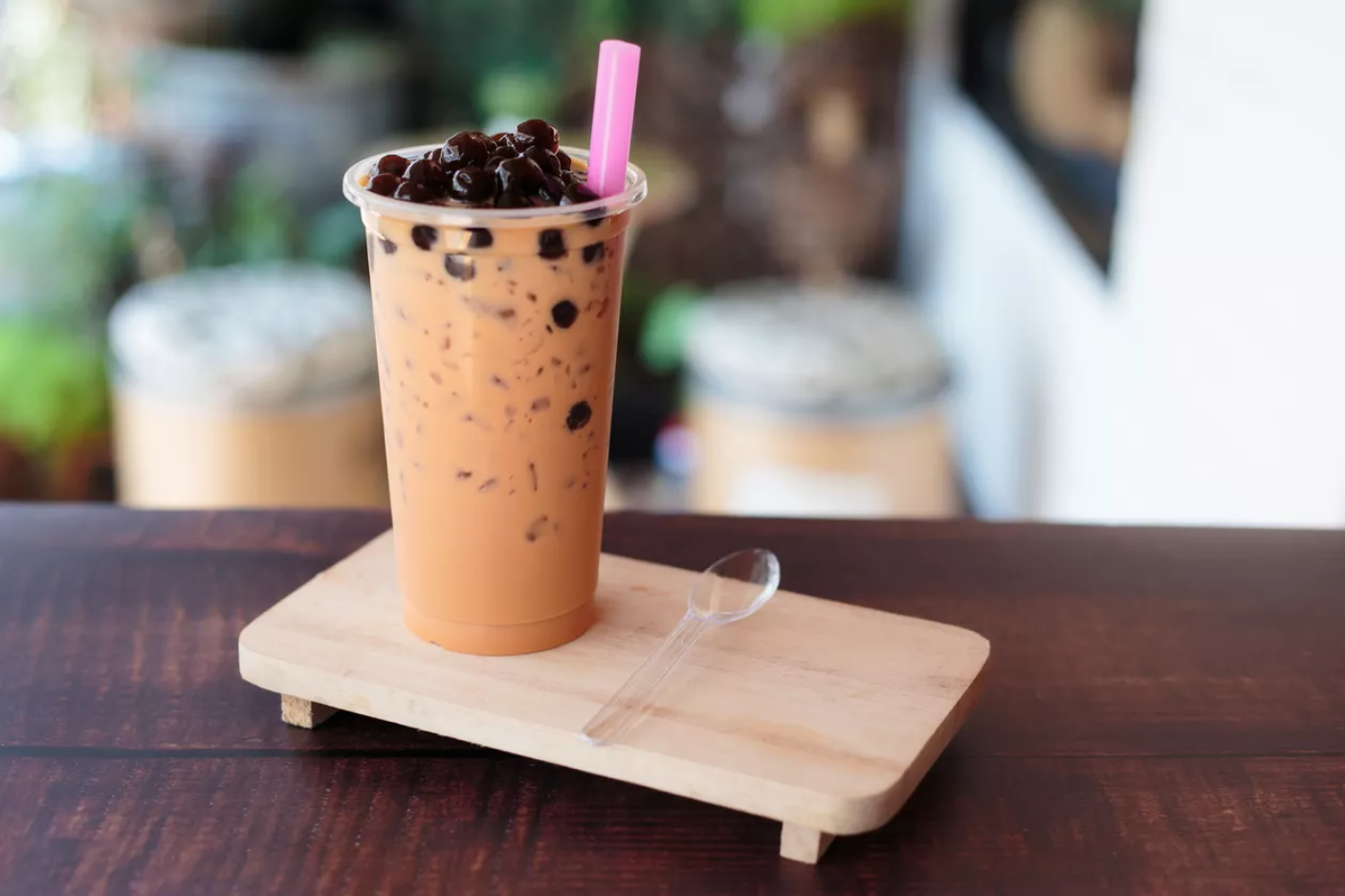 Image of a glass of milk tea with tapioca pearls and a straw.