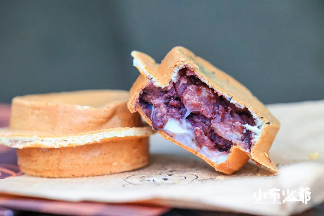 Image of a waffle dough 'wheel cake' with red bean filling spilling out.